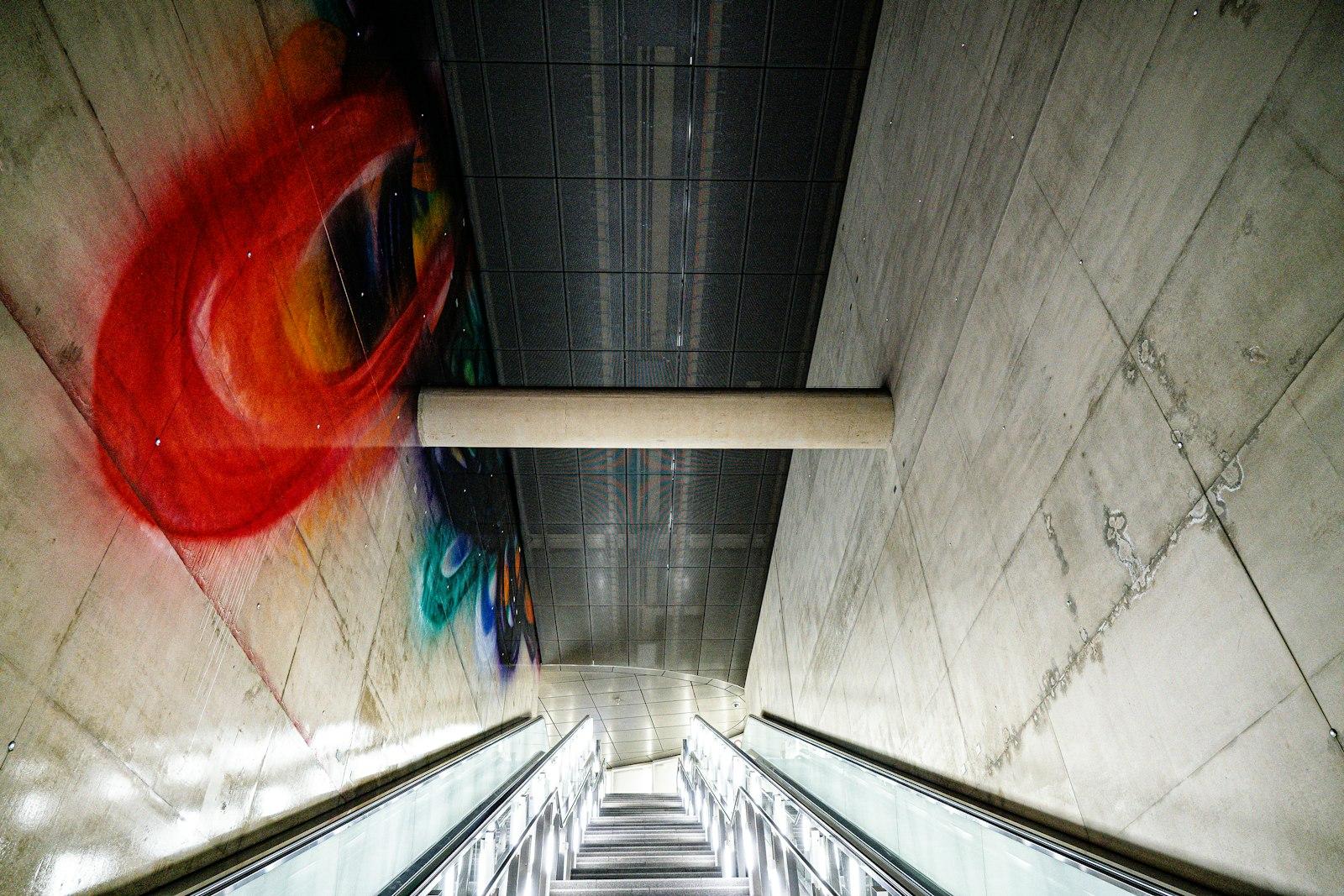 Graffiti art on a concrete wall above escalators